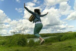 femme Heureusement sauté en haut avec sa bras tendu contre le ciel photo