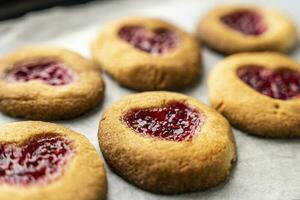 fait maison biscuits décoré avec framboise confiture dans le forme de une cœur photo