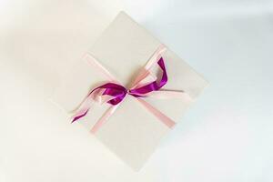 grand blanc cadeau boîte lié avec une rouge ruban sur une blanc Contexte photo