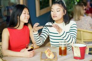 Enchanté asiatique femelle copains prise photo de nourriture dans café