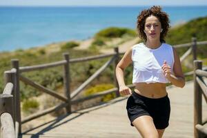 en forme femme le jogging sur en bois sentier sur ensoleillé journée photo