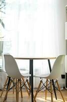 le intérieur de le maison avec grand les fenêtres et Accueil les plantes rond tableau, chaises, blanc grenier. minimalisme, blanc rideau photo