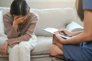 psychologie, dépression. triste, Souffrance asiatique Jeune femme, consultant avec psychologue, psychiatre tandis que patient conseils mental problème avec médecin à clinique. encourageant, thérapie, santé se soucier. photo