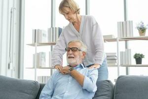 santé, corps muscles rigide problème de Sénior couple, caucasiens mature, adulte retraité mari, épouse douleur avec retour douleur mal en portant masser frottement épaule blesser ou douloureux, douloureux séance sur canapé. photo