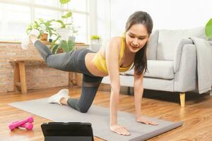 planche aptitude, magnifique asiatique Jeune femme dans tenue de sport, en utilisant tablette pour en ligne formation force muscles entraînement, exercice formation à Accueil pour en bonne santé corps fort athlétique adapter, actif mode de vie. photo