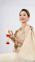 luxe portrait de une magnifique thaïlandais fille dans traditionnel thaïlandais costume en portant guirlande isolé sur blanc arrière-plan, identité culture de Thaïlande, identité culture de Asie photo