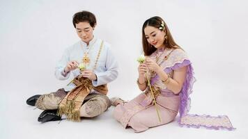 asiatique couple dans traditionnel thaïlandais costume fabrication et décorer lotus isolé sur blanc arrière-plan, Thaïlande traditionnel culture photo