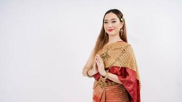 luxe portrait de une magnifique thaïlandais fille dans traditionnel thaïlandais costume posant à Payer le respect avec souriant isolé sur blanc Contexte photo