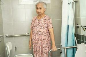 asiatique personnes âgées femme patient utilisation toilette salle de bains manipuler Sécurité dans allaitement hôpital, en bonne santé fort médical concept. photo