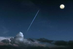 jet avion avec traînée en volant par des nuages dans le nuit ciel avec plein lune embrasé et étoilé photo