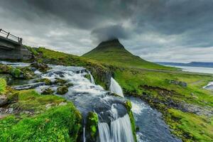 de mauvaise humeur des nuages plus de kirkjufell Montagne et cascade écoulement dans été à Islande photo