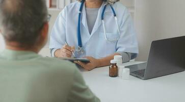 mature asiatique Masculin médecin parlant avec le sien patient, expliquant le procédure à vieux dame. photo