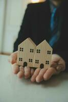 femme femme mains tenant le modèle de maison, petite maison de jouet blanche miniature. assurance habitation de rêve déménagement et concept immobilier photo
