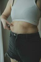 grosse femme, gros ventre, joufflu, main de femme obèse tenant la graisse du ventre excessive avec ruban à mesurer, concept de mode de vie de régime alimentaire femme photo