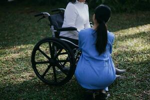 jeune physiothérapeute asiatique travaillant avec une femme âgée sur la marche avec un déambulateur photo