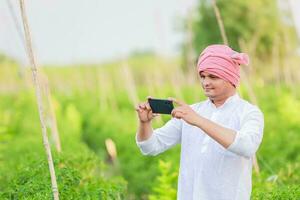 Jeune Indien agriculteur montrant intelligent téléphone , agriculteur parlant sur téléphone dans cultiver, content Indien agriculteur photo