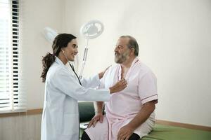 femelle médecins dans uniforme en bonne santé vérifier blanc Masculin les patients dans examen manteau par stéthoscope, et bilans et conseiller santé se soucier diagnostic à clinique hôpital, et rendez-vous visite. photo