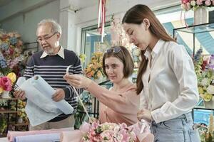 équipe de magasin de fleurs, jeunes belles ouvrières fleuristes avec l'ancien propriétaire organisant et décorant un bouquet de fleurs fraîches, souriant avec un travail heureux dans un magasin coloré, petite entreprise PME entrepreneur. photo