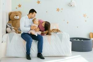 content Jeune famille séance sur le lit dans le enfants pièce et bavardage avec leur Un an fille photo