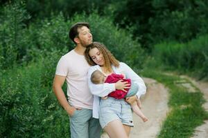 une mère et père avec une enfant fils en marchant dans le les bois. famille vacances en voyageant avec une enfant photo