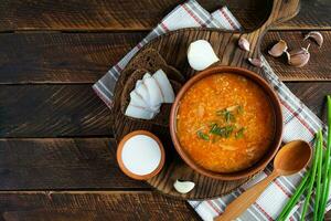 chou soupe dans bol avec vert oignon, pain et salo sur en bois Contexte. Haut vue photo