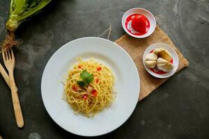 Aglio e olio. italien Pâtes spaghetti, Aglio olio e pepperoni ,spaghetti avec ails, olive pétrole et Chili poivrons sur assiette sur table photo