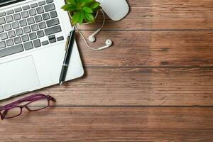 vieux bois bureau table avec portable ordinateur, stylo et lunettes. Haut vue photo