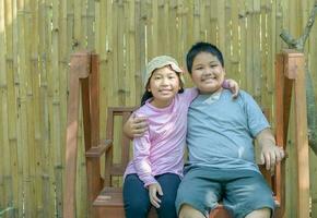 content frère et sœur sourire et asseoir sur balançoire. photo