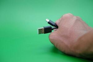 main en portant USB type une à USB micro b câble isolé sur vert Contexte. photo