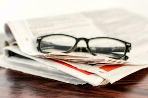 journal et en train de lire des lunettes sur en bois tableau. photo