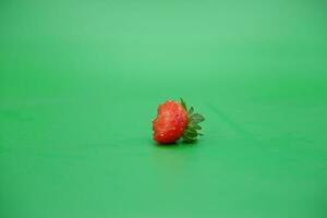 une rouge fraise isolé sur une vert Contexte. mordu des fraises. photo