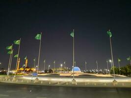 Djeddah, saoudien Saoudite, juin 2023 - une magnifique vue de saoudien arabe drapeaux en volant à Djeddah corniche route intersection à nuit. photo