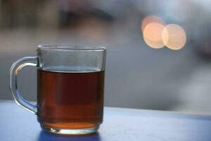 une verre de chaud thé sur une Contexte dans le Matin. photo
