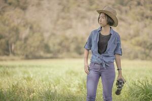 femme porter un chapeau et tenir des jumelles dans un champ d'herbe photo