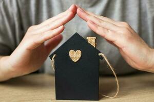 la main de la femme a couvert la petite maison de jouet. notion d'assurance habitation photo