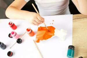 une petite fille peint un renard jouet en argile. notion de bricolage photo
