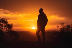 le silhouette de une Jeune homme contre le Contexte de le chaleur de une d'or coucher de soleil, une magnifique vue de le ciel génératif ai photo