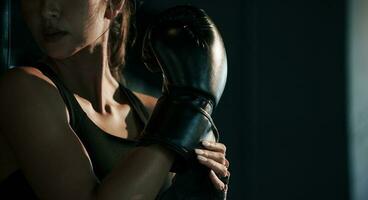 fermer Jeune femme portant boxe gant dans le salle de sport. photo