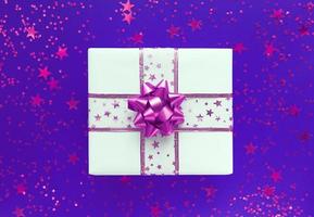 coffret cadeau blanc avec noeud rose et étoiles sur fond violet