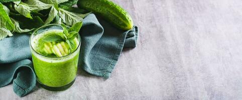 smoothie de concombre et menthe dans une verre, des légumes et feuilles sur une gris Contexte la toile bannière photo