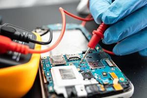 Technicien réparant l'intérieur du téléphone mobile par circuit intégré de fer à souder photo