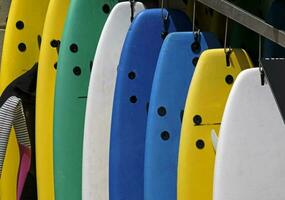 plusieurs coloré planches de surf pendaison dans de face de une planche de surf de location endroit dans Ericeira, le Portugal photo