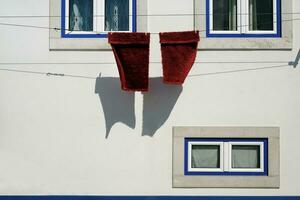 calme scène avec une blanc mur avec deux rouge les serviettes accroché en dehors à sec photo