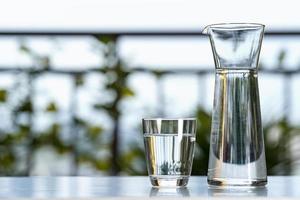 Boire un pot en verre d'eau avec du verre sur la table à la maison de jardin