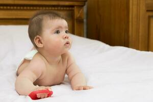 charmant mignonne bébé fille mensonges sur sa ventre sur une lumière Contexte photo