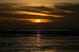 Contexte silhouette soir le coucher du soleil de le boueux mer dans Thaïlande photo