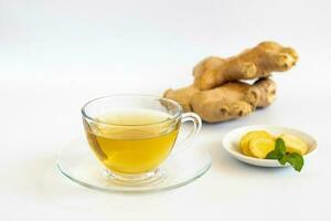 une tasse de thé avec racine de gingembre, citron vert, cannelle et théière sur fond blanc. concept de boisson santé. photo