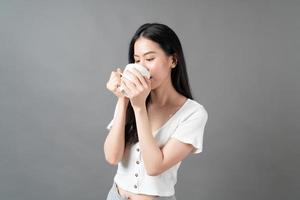 jeune femme asiatique avec un visage heureux et une main tenant une tasse de café photo