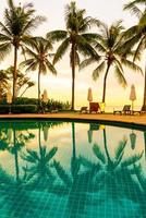 Parapluie et chaise autour de la piscine de l'hôtel resort avec lever de soleil le matin photo