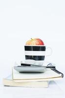 pomme rouge en tasse et calculatrice et notes de livre sur fond blanc photo